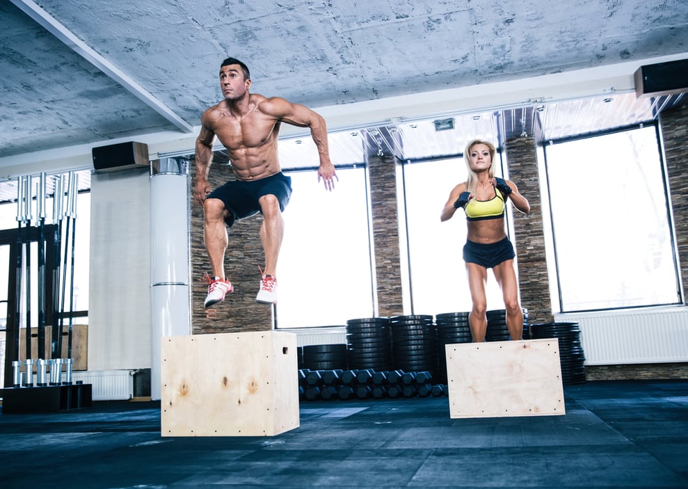 Group of man and woman jumping on fit box at gym Group of man and woman jumping on fit box at gym