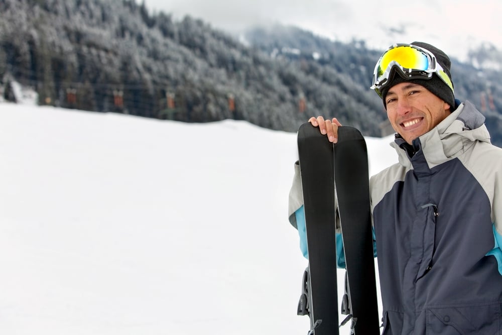happy skier smiling with his skiis in the trail happy skier smiling with his skiis in the trail